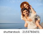 Small photo of Young cheerful happy couple two friends family man woman in white clothes boyfriend give piggyback ride to joyful, girlfriend sit on back at sunrise over sea beach ocean outdoor seaside in summer day