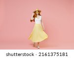 Full length body young nice smiling happy redhead woman 20s ginger long hair wear straw hat glasses summer clothes flow yellow maxi pleated skirt isolated on pastel pink background studio portrait