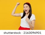 Small photo of Happy fun excited jubilant young woman of Asian ethnicity 20s years old wears white t-shirt doing winner gesture celebrate clenching fists say yes isolated on plain yellow background studio portrait