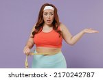 Small photo of Young confused sad indignant chubby overweight plus size big fat fit woman in top hold measure tape waist spread hand warm up train isolated on purple color background home gym Workout sport concept.