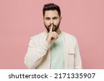 Small photo of Young smiling happy secret man 20s wear trendy jacket shirt say hush be quiet with finger on lips shhh gesture isolated on plain pastel light pink background studio portrait. People lifestyle concept