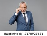 Small photo of Perplexed elderly gray-haired mustache bearded business man in classic blue suit shirt tie isolated on grey wall background studio portrait. Achievement career wealth business concept. Looking camera