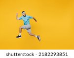 Full body side view strong young fitness trainer instructor sporty man sportsman wear headband blue t-shirt jump high run fast look aside isolated on plain yellow background. Workout sport concept.