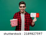 Young surprised fun excited man he in 3d glasses watch movie film hold bucket of popcorn ticket in cinema point index finger camera on you isolated on plain dark green color background studio portrait