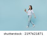 Full body young happy smiling woman she 20s wears casual blouse hold takeaway delivery craft paper brown cup coffee to go isolated on pastel plain light blue background studio People lifestyle concept
