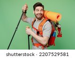Young fun traveler white man carry backpack stuff hold trakking poles isolated on plain green background Tourist lead active healthy lifestyle walk on spare time Hiking trek rest travel trip concept