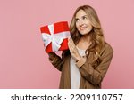 Small photo of Young wistful dreamful successful employee business woman 30s she wear casual classic jacket hold red present box with gift ribbon bow isolated on plain pastel light pink background studio portrait