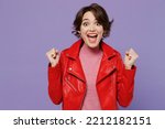 Small photo of Young smiling happy woman 20s wear red leather jacket doing winner gesture celebrate clenching fists say yes isolated on plain pastel light purple background studio portrait. People lifestyle concept