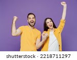 Small photo of Young overjoyed excited couple two friends family man woman together in yellow casual clothes doing winner gesture celebrate clench fists say yes isolated on plain violet background studio portrait