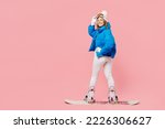 Back view snowboarder woman wear blue suit goggles mask hat ski padded jacket snowboarding look camera isolated on plain pastel pink background. Winter extreme sport hobby weekend trip relax concept