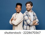 Side view young two friends happy cool men 20s wear white casual shirts together hold hands crossed folded look to each other isolated plain dark royal navy blue background. People lifestyle concept