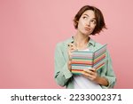 Young woman 20s she wear green shirt white t-shirt writing down in notebook diary remind memories and make list of dreams isolated on plain pastel light pink background studio People lifestyle concept