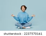 Full body young woman wear knitted sweater holding spreading hands in yoga om aum gesture relax meditate try to calm downisolated on plain pastel light blue cyan background. People lifestyle concept