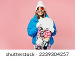Snowboarder excited woman wear blue suit goggles mask hat ski padded jacket hold snowboard behind neck isolated on plain pastel pink background. Winter extreme sport hobby weekend trip relax concept