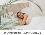 Smiling young woman in casual casual clothes lying in bed hands folded under head look camera rest relax spend time in bedroom lounge home in own room house wake up dream be lost in reverie good day