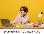 Small photo of Young tired sad weary employee IT business woman wear casual shirt sit work at office desk using laptop pc computer prop up chin isolated on plain yellow color background. Achievement career concept