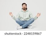 Small photo of Full body spiritual tranquil young man wear mint hoody hold spreading hands in yoga om aum gesture relax meditate try to calm down isolated on plain solid white background. People lifestyle concept