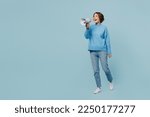 Full body shocked excited fun happy young woman wear knitted sweater hold in hand megaphone scream announces discounts sale Hurry up isolated on plain pastel light blue cyan background studio portrait