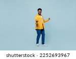 Small photo of Full size excited young man of African American ethnicity 20s wear yellow shirt doing winner gesture celebrate clenching fists say yes isolated on plain pastel light blue background studio portrait.