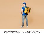 Full body back view delivery guy employee man wear blue cap t-shirt uniform workwear yellow thermal food bag backpack work as dealer courier isolated on plain light beige background. Service concept