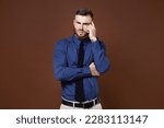 Small photo of Preoccupied worried bearded young business man wearing blue shirt tie put hand on head looking camera isolated on brown colour background studio portrait. Achievement career wealth business concept