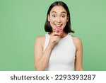 Small photo of Young happy fun woman wearing white clothes hold in hand biting donut dessert look camera isolated on plain pastel light green background. Proper nutrition healthy fast food unhealthy choice concept