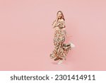 Full body side profile view young blonde caucasian woman wear summer casual clothes hold face raise up leg look camera isolated on plain pastel light pink background studio portrait. Lifestyle concept