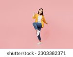 Full body excited young woman of Asian ethnicity wear yellow shirt white t-shirt doing winner gesture celebrate clenching fists say yes isolated on plain pastel light pink background studio portrait
