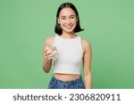 Small photo of Young happy woman wear white clothes hold drink clear fresh pure still water from transparent glass isolated on plain pastel light green background. Proper nutrition healthy fast food choice concept