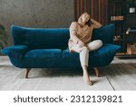 Small photo of Full size body calm elderly woman 50s years old wears casual clothes sits on blue sofa prop up head close eyes dream stay at home flat rest relax spend free spare time in living room indoor grey wall