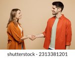 Small photo of Side view young smiling happy couple two friends family man woman wear casual clothes looking to each other shaking hands together isolated on pastel plain light beige color background studio portrait