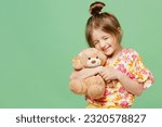 Little happy child kid girl 6-7 year old wear casual clothes have fun hold hug teddy bear plush toy isolated on plain pastel green background studio portrait Mother's Day love family lifestyle concept