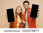 Small photo of Young smiling couple two friend family man woman wear casual clothes hold in hand use showing close up mobile cell phone with blank screen workspace area together isolated on plain beige background