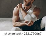 Small photo of Cropped close up young ill sporty athletic sportsman man wear white tank shirt black shorts feel bad suffer from pain spasm in hand elbow shoulder warm up train indoor at gym Workout sport concept