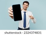Small photo of Young employee business man corporate lawyer wear classic formal shirt tie work in office hold use show blank screen workspace area mobile cell phone isolated on plain blue background studio portrait