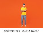 Full body smiling young man wear pyjamas jam sleep eye mask rest relax at home hold hands crossed folded look camera isolated on plain orange background studio portrait. Good mood night nap concept