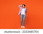 Small photo of Full body angry mad astonished sad young woman she wear purple shirt white t-shirt casual clothes hold head use mobile cell phone isolated on plain orange background studio portrait. Lifestyle concept