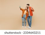 Full body young couple two friends family man woman wear casual clothes together do selfie shot on mobile cell phone post photo on social network isolated on pastel plain light beige color background