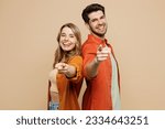 Small photo of Side view young couple two friends family man woman wear casual clothes point index finger camera you stand back to back together isolated on pastel plain light beige color background studio portrait