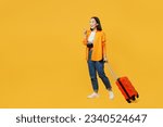 Side view young woman wear summer clothes walk go with suitcase point aside isolated on plain yellow background. Tourist travel abroad in free spare time rest getaway. Air flight trip journey concept