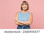 Small photo of Elderly smiling fun cheerful blonde woman 50s years old she wears blue undershirt casual clothes hold hands crossed folded look camera isolated on plain pastel light pink background. Lifestyle concept