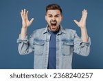Small photo of Distempered unnerved concerned aggrieved young brunet man 20s wears denim jacket spreading hands screaming shouting isolated on dark blue background studio portrait. People emotions lifestyle concept