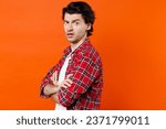 Small photo of Side view of perplexed puzzled young brunet man 20s wearing white t-shirt red checkered shirt posing holding hands crossed looking camera isolated on orange color wall background studio portrait
