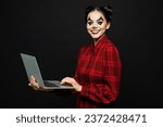 Young IT woman with Halloween makeup face art mask wear clown costume red dress work hold using laptop pc computer isolated on plain solid black background studio portrait. Scary holiday party concept