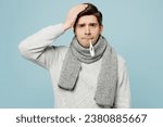 Small photo of Young sad ill sick man wear gray sweater scarf hold keep thermometer in mouth isolated on plain blue background studio portrait. Healthy lifestyle disease virus treatment cold season recovery concept