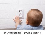 Unrecognizable caucasian boy is playing with open electrical outlet. Baby wires. Dangerous games with open electric socket. 