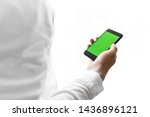 Mockup image of hand holding black mobile phone with green screen