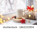 Hot tea, coffee. Winter background with cup of coffee, tea, on the window, knitted scarf and gift. Christmas greeting card concept