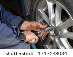 Small photo of Mechanic without gloves is changing wheel on car with pneumatic wrench or backyard mechanics impact wrench. Close-up