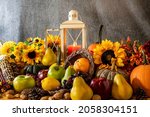 Small photo of Thanksgiving cornucopia overflowing with fruit nuts pumpkins sunflowers and burning candle